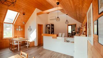 A cozy wooden interior with a dining area, a kitchen counter, and a large window providing natural light.