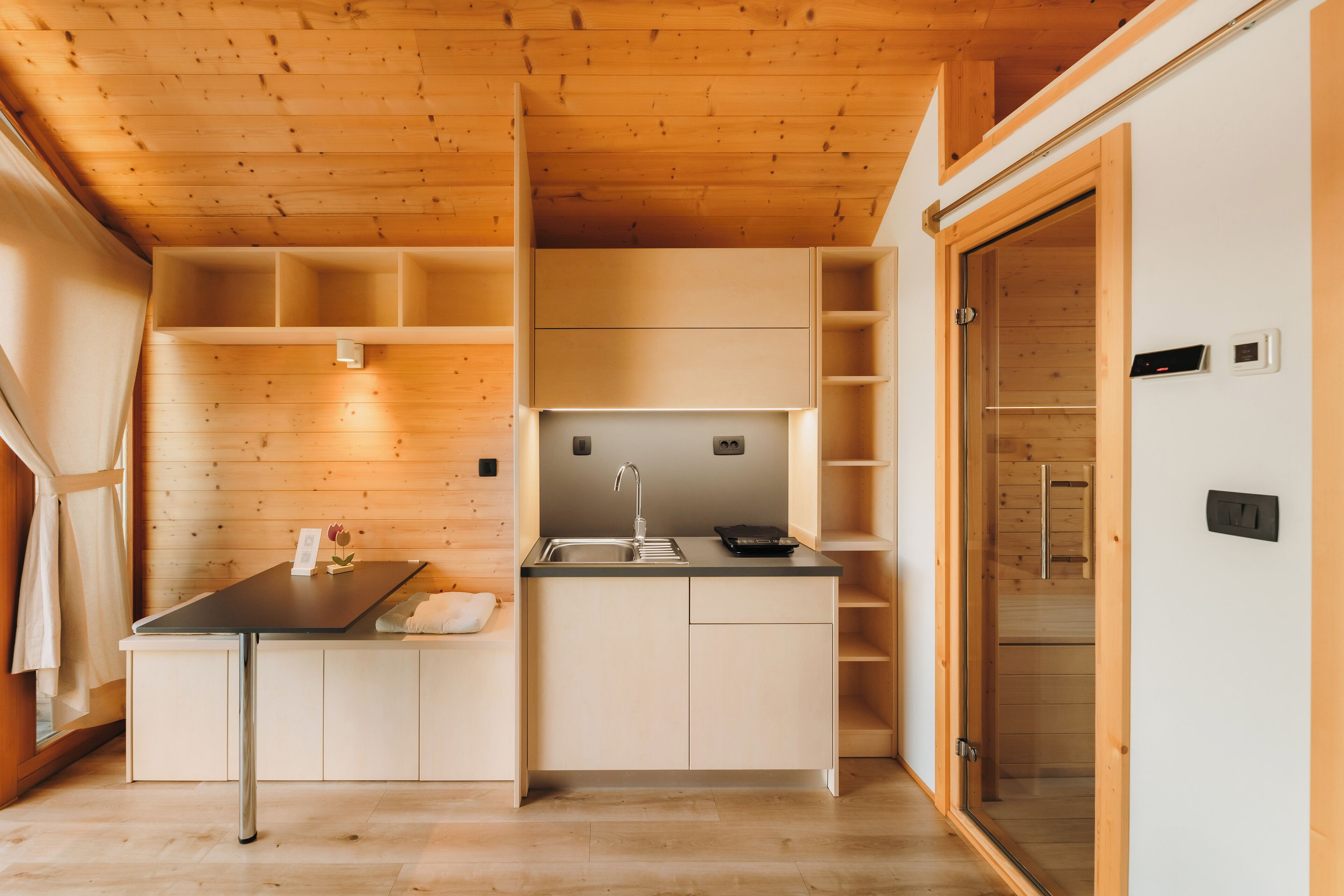 A compact kitchen with wooden walls, a built-in sink, and a small countertop.