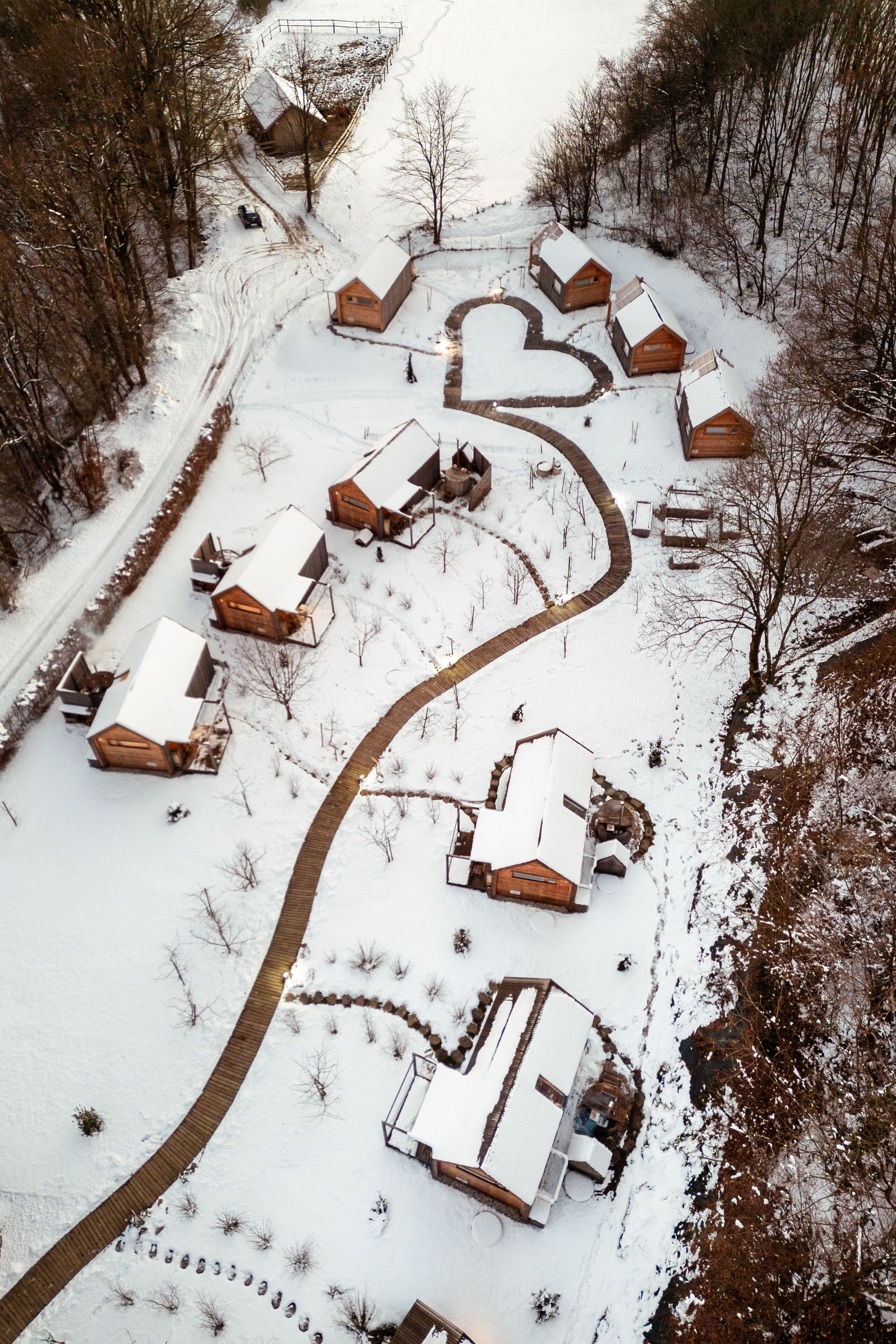 A snow-covered area with several wooden cabins arranged in a heart shape.