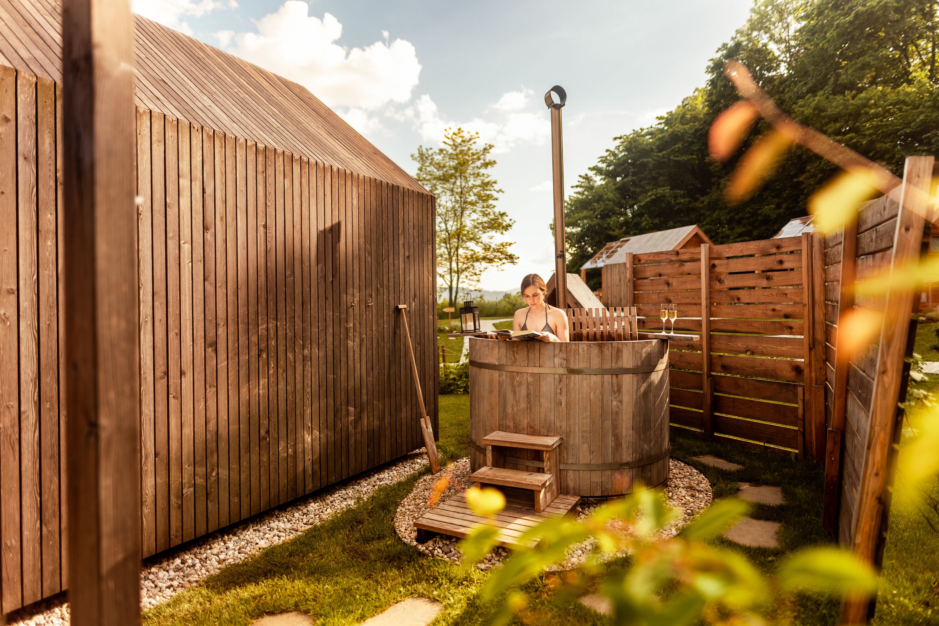 Zona de sauna exterior de madera con un banco de madera y un escalón que lleva a un jacuzzi.