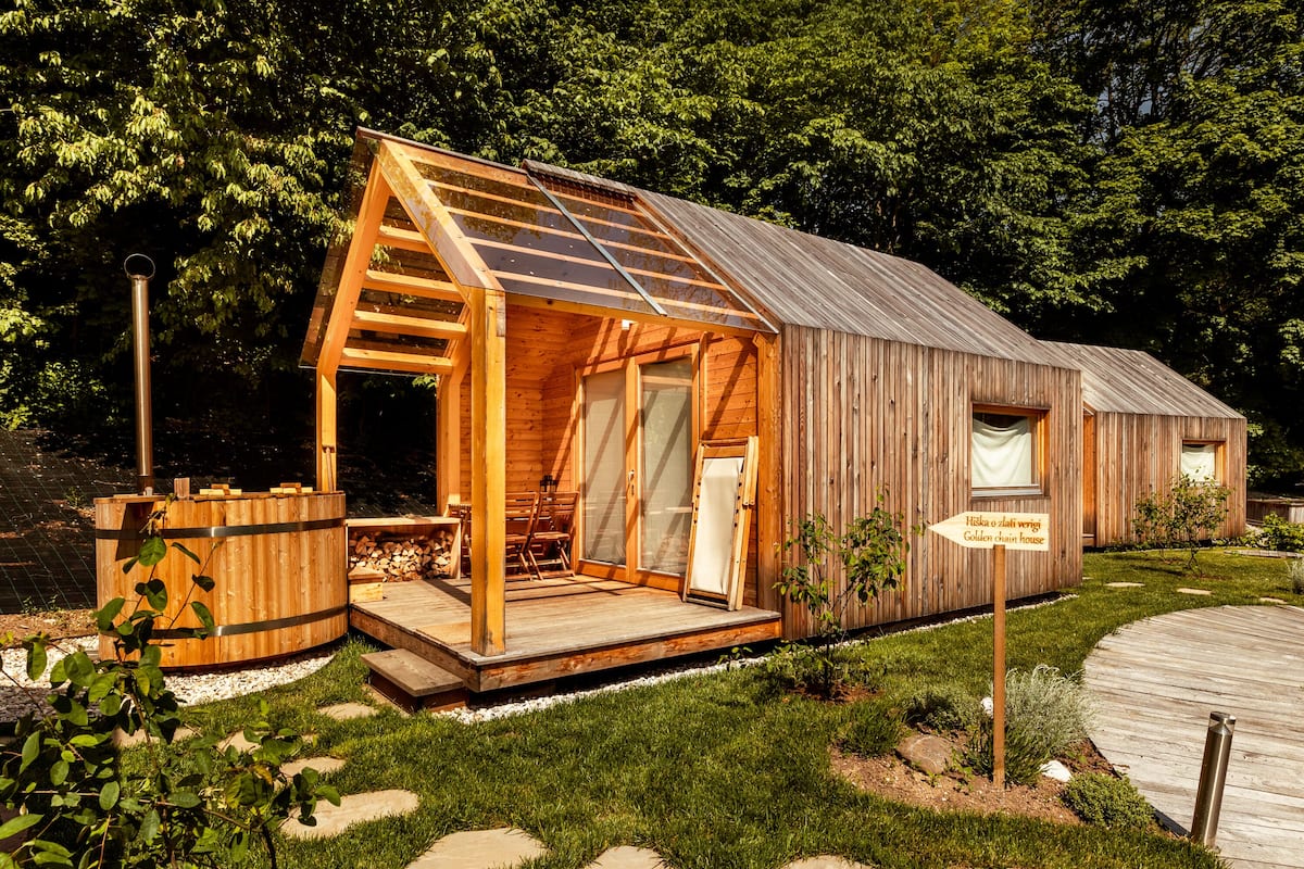 A wooden cabin with a glassed-in porch, a wooden deck, and a sign indicating a "Golden chain house."