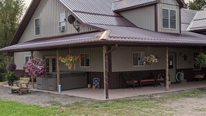 A large two-story house with a covered porch, outdoor seating, and hanging flower baskets.