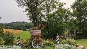 A garden with a wooden bench, a birdhouse, and two striped poles.