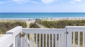A beach view with a white fence and beach umbrellas.