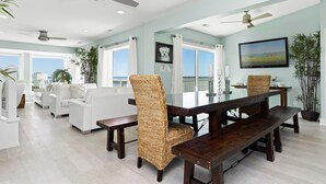 A spacious living area with a dining table, wicker chairs, and a sofa.