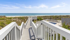 A wooden boardwalk leading to a beach with a clear view of the ocean.