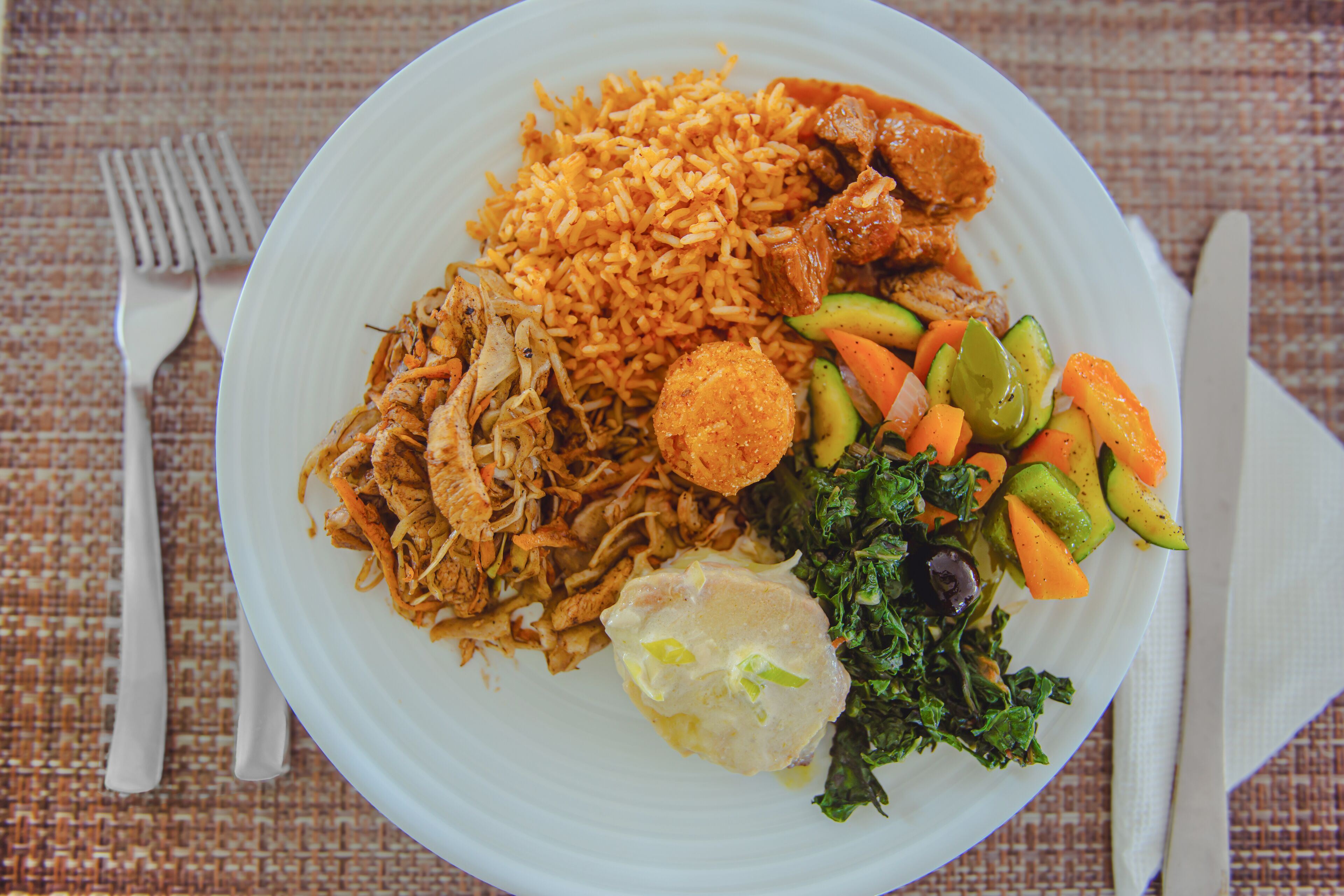 A plate of food with rice, meat, and vegetables.