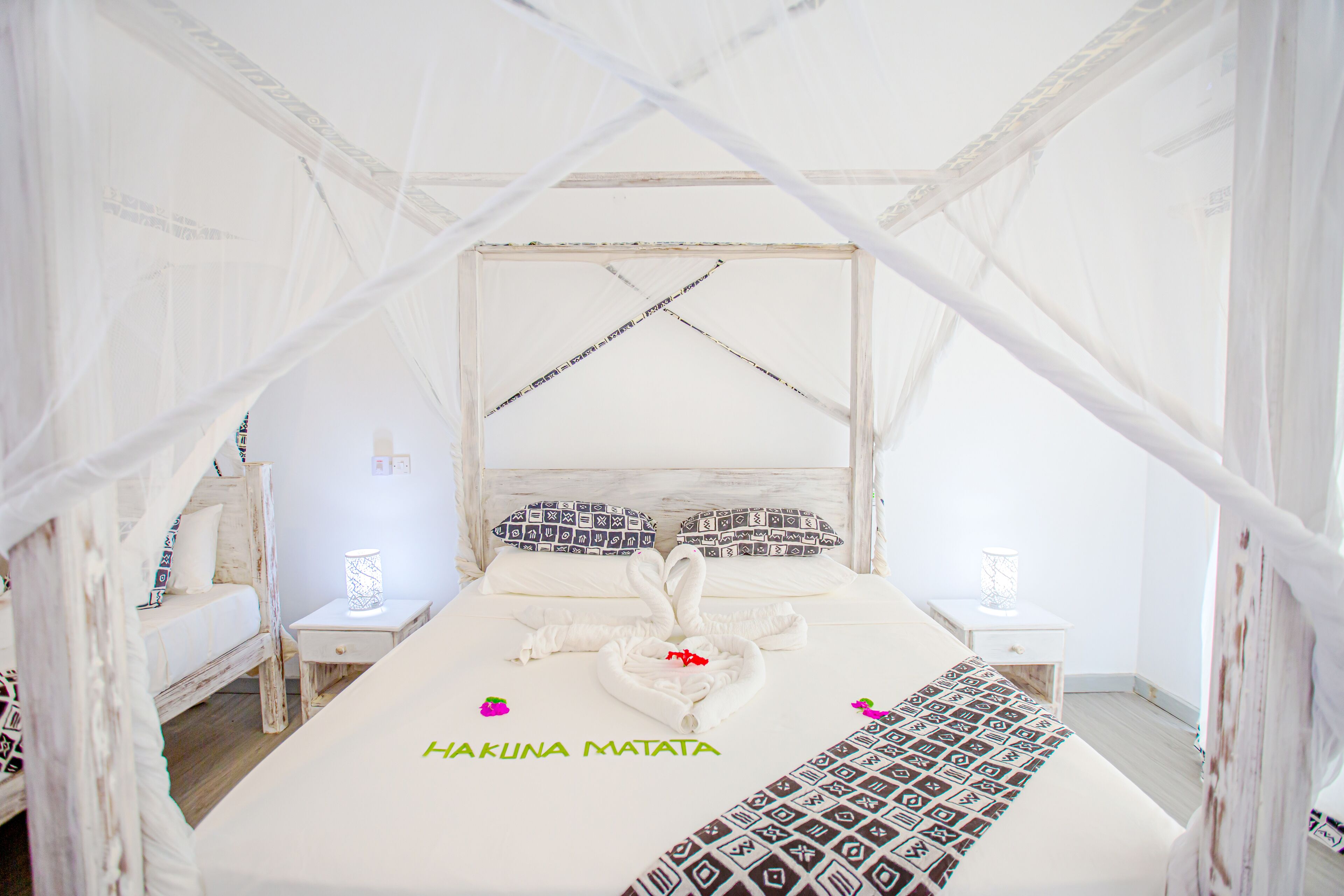 Un dormitorio blanco con forma de tienda de campaña, una cama, mesitas de noche y un dosel.