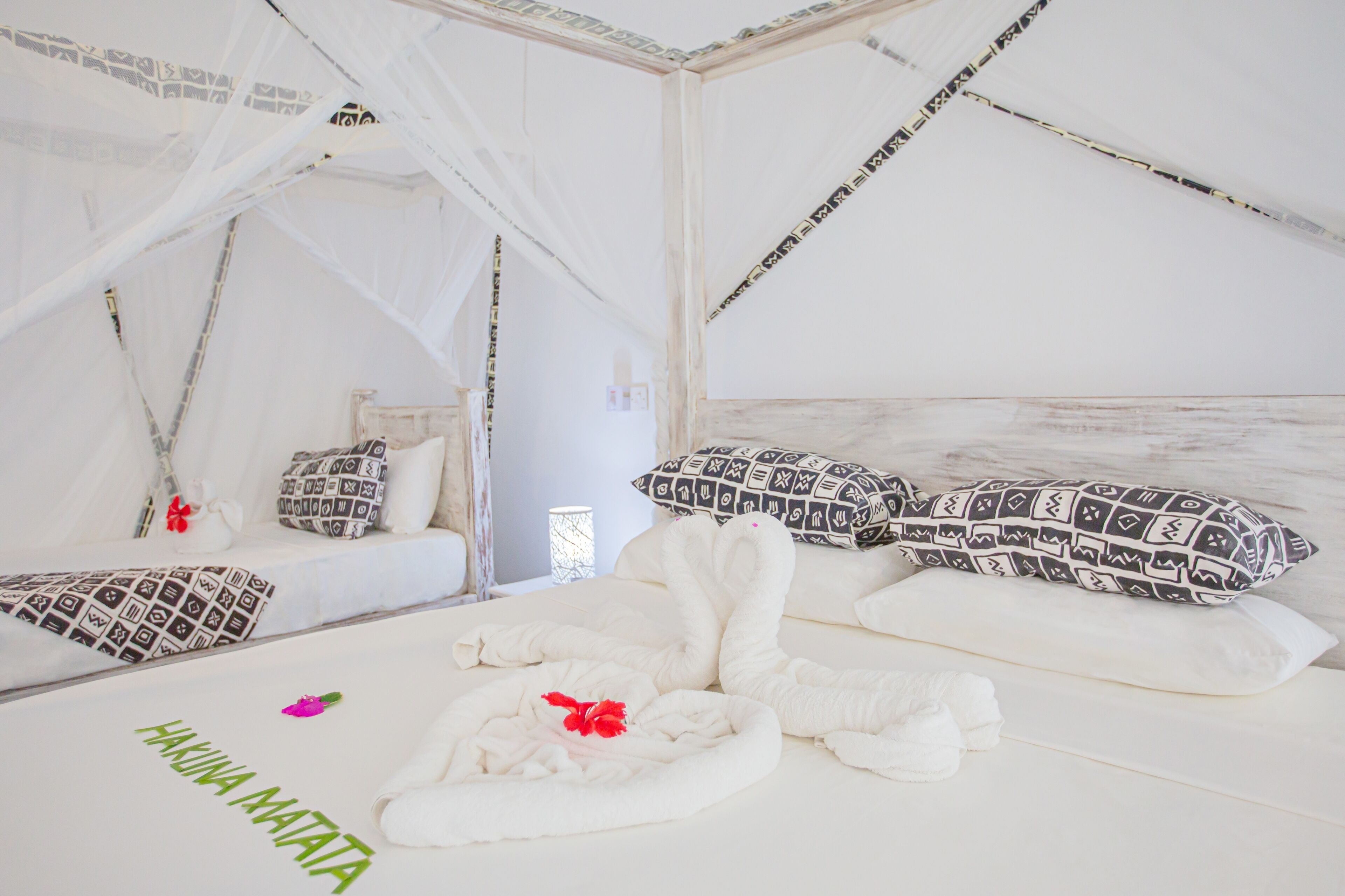 A white, tent-like room with a bed, pillows, and a towel.