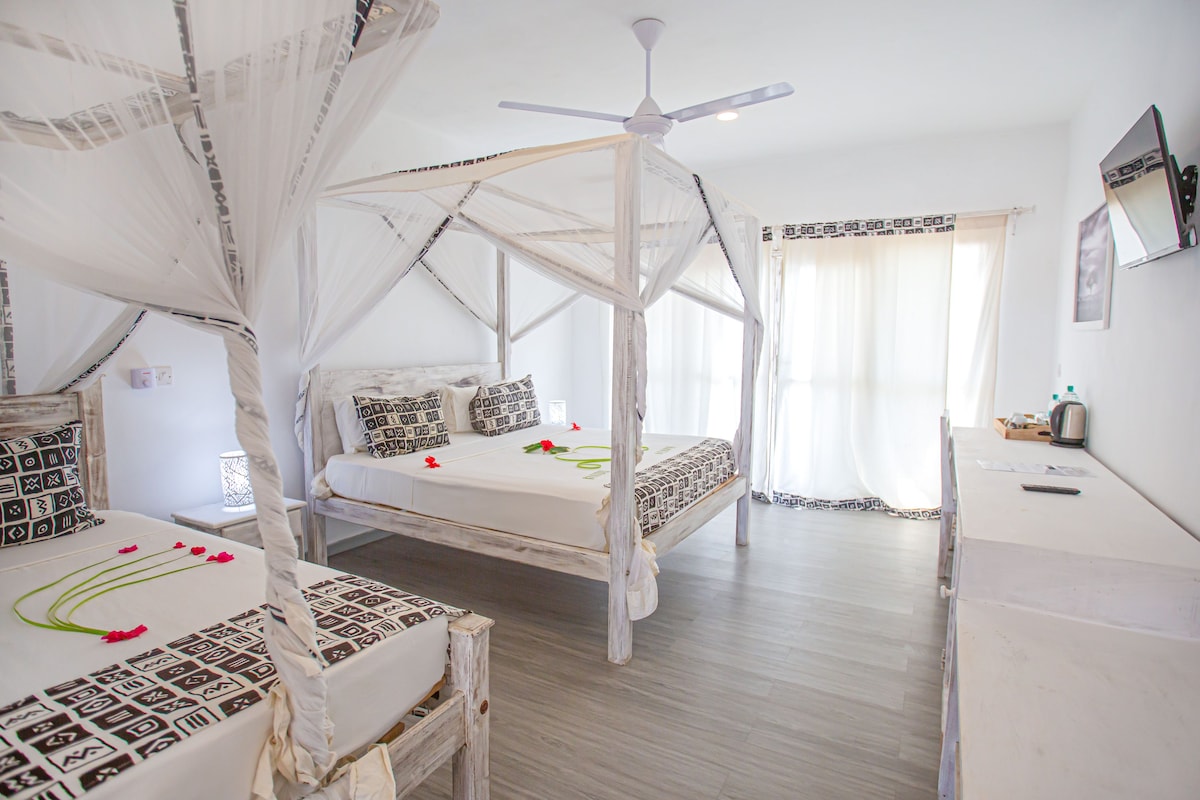 A bedroom with a canopy bed, a desk, and a ceiling fan.