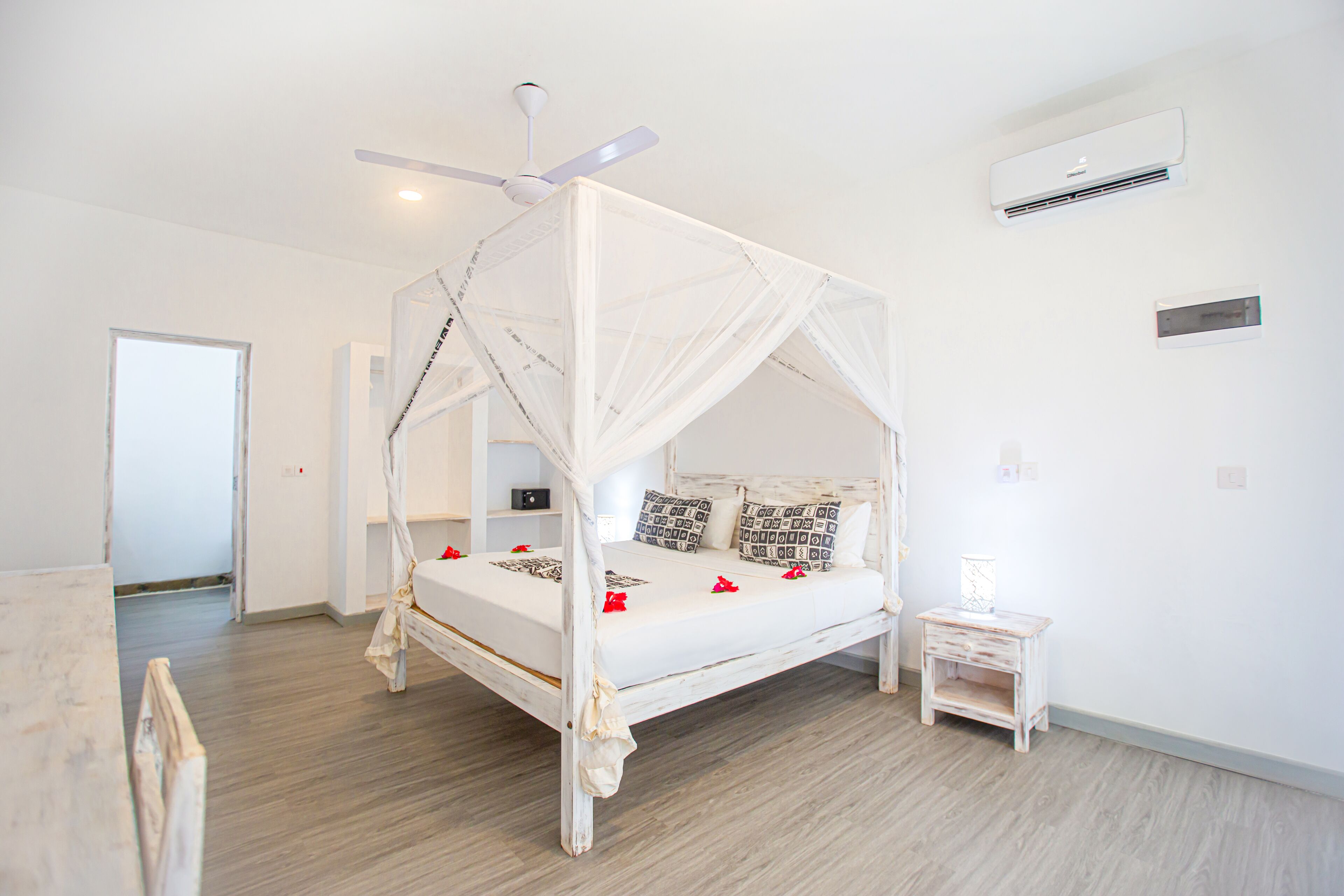 A four-poster bed with a canopy, a ceiling fan, and an air conditioning unit on the wall.