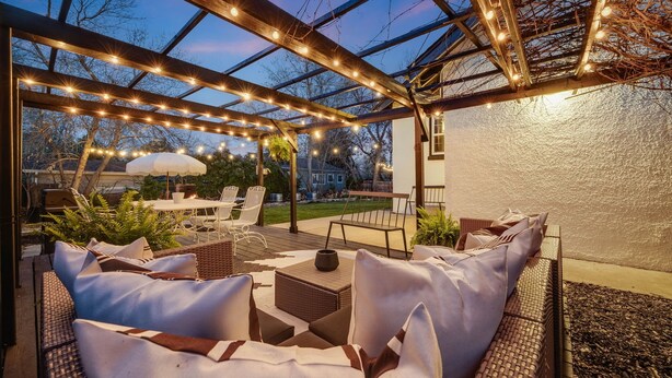 An outdoor patio with wicker furniture, string lights, and a pergola. - Charming 3 Bedroom 1940s Farm House (Lakewood)