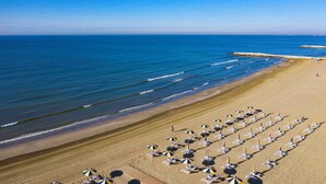 A beach with rows of sun loungers and umbrellas, a sandy shore, and the ocean. - Mobile home with terrace (Cavallino-Treporti)