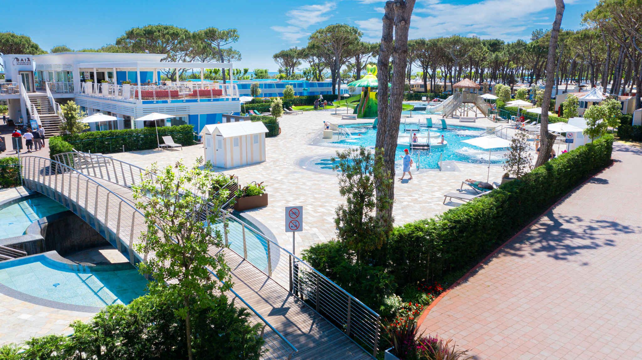 Ein Resort mit mehreren Schwimmbecken, einem überdachten Sitzbereich und einem Gebäude in Blau und Weiß.