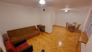 A spacious living area with a wooden herringbone floor, a brown sofa, a small table, and a dining set with chairs. - Cottage off the beaten track 3 rooms 2 bathrooms

 (Kraków)