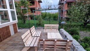 A wooden deck with benches and a stone wall, surrounded by greenery and a building in the background. - Cottage off the beaten track 3 rooms 2 bathrooms

 (Kraków)