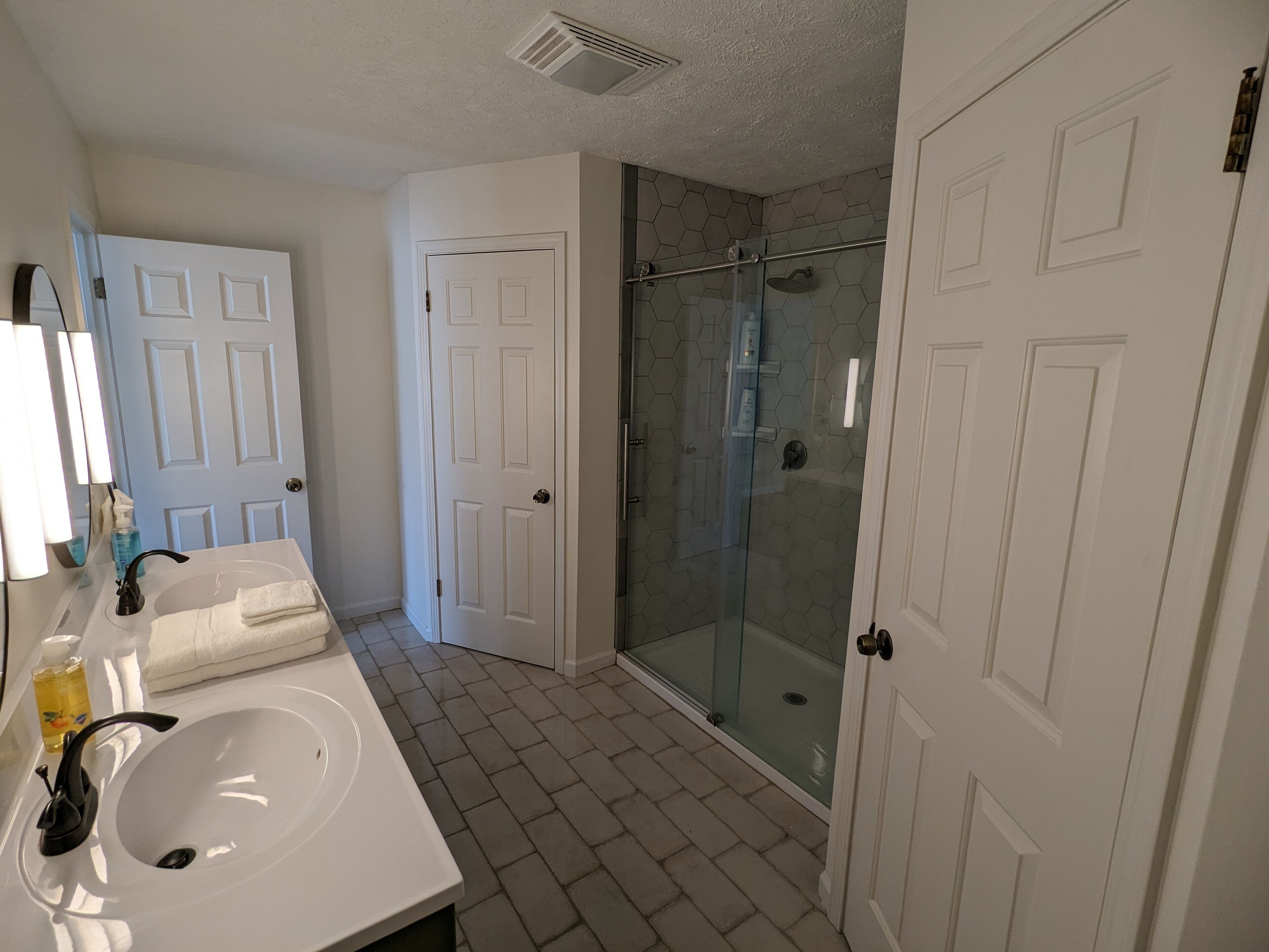 A bathroom with a white sink, mirror, and two white doors.