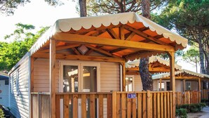 Una cabaña de madera con un porche cubierto, una placa con el número 319 y un árbol en primer plano.