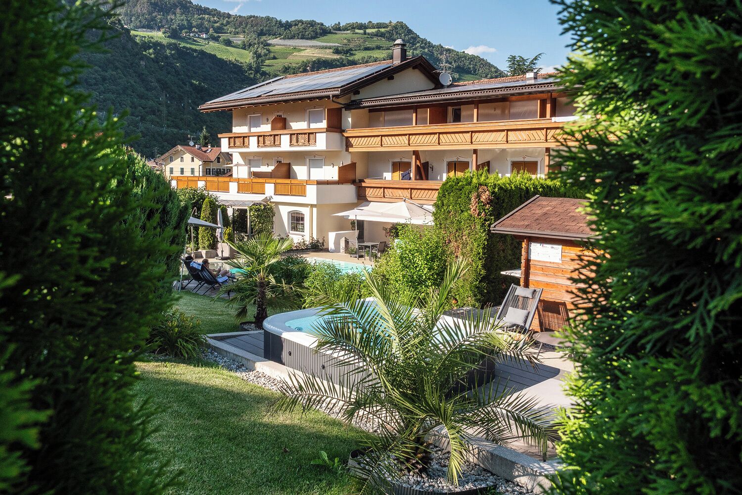 Un edificio di due piani con piscina, area salotto all'aperto e vista su un paesaggio montano.