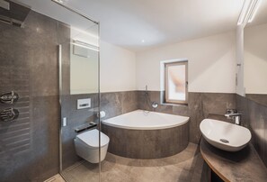 Une salle de bain moderne dotée d’une douche à parois de verre, de toilettes sur pied, d’un lavabo sur pied et d’une grande baignoire.