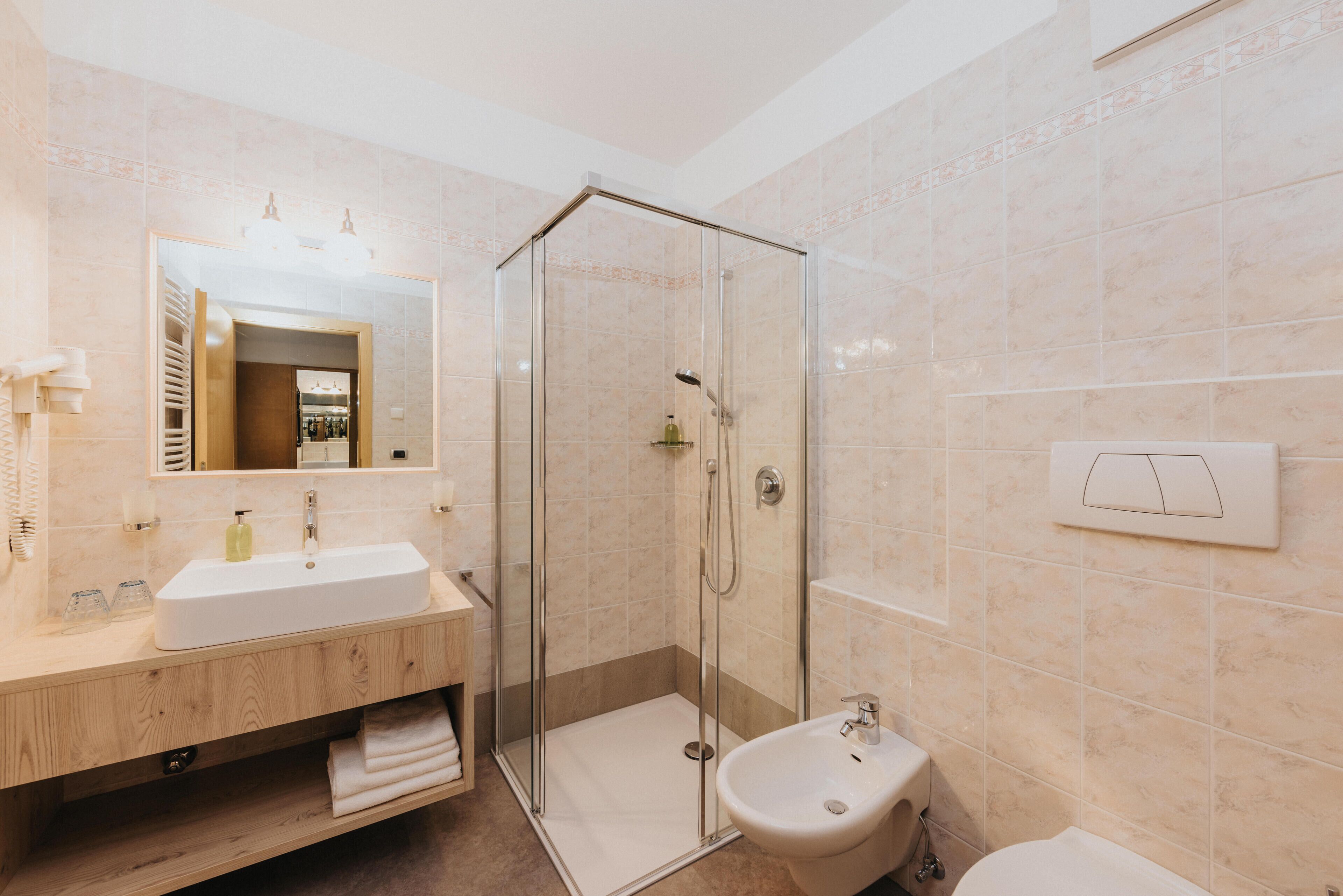 Un baño moderno con ducha de vidrio, lavamanos y bidé.