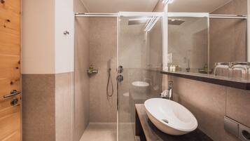 A modern bathroom with a glass-enclosed shower, a white sink, and a large mirror.