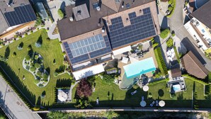 An aerial view of a residential area with solar panels, a swimming pool, and well-maintained gardens. - Hotel Bischofhof - Bistro Jasmin (Chiusa)