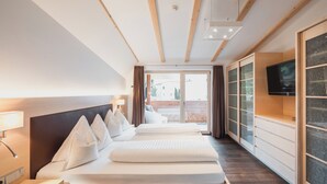 A hotel room with a large bed, a TV, a desk, and a view of the outside. - Hotel Bischofhof - Bistro Jasmin (Chiusa)