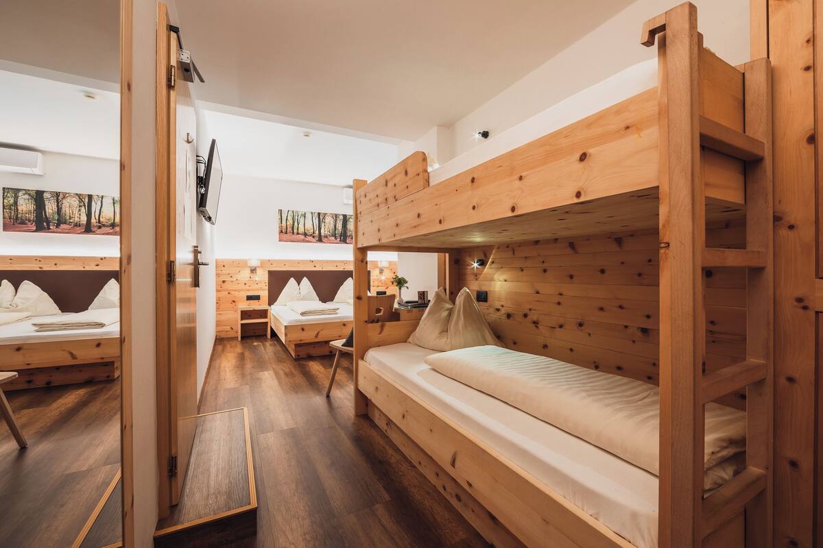 Een kamer met stapelbedden, houten wanden, een flatscreen televisie en een schilderij aan de wand.
