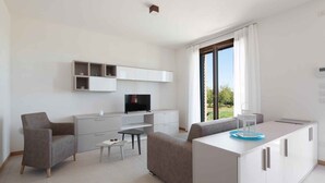 A modern, minimalist living room with a sofa, TV, and built-in cabinets.