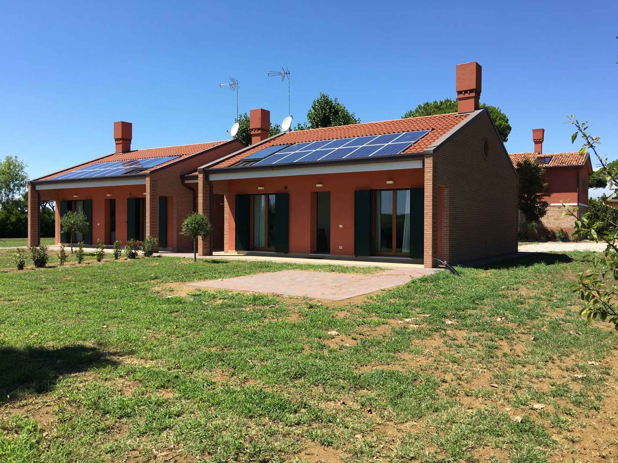 Een modern huis met twee verdiepingen, een bakstenen gevel, grote ramen en een plat dak met zonnepanelen.