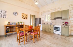 Enjoy meals with family and friends at the dining table, surrounded by a fully equipped kitchen with a refrigerator and oven.
