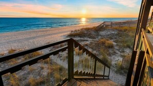 Un escalier en bois menant à une plage d’où l’on peut admirer le coucher de soleil.