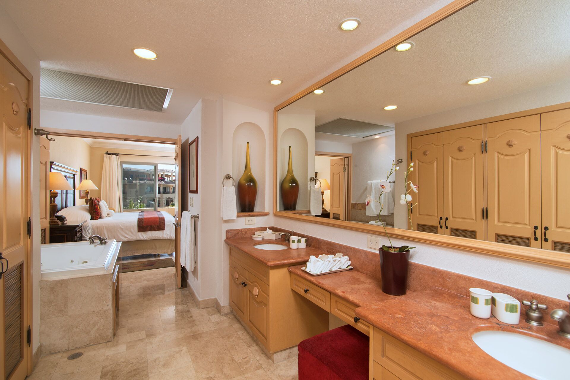 A hotel bathroom with a large mirror, a sink, and a vanity. There is a window with a view of the outside.