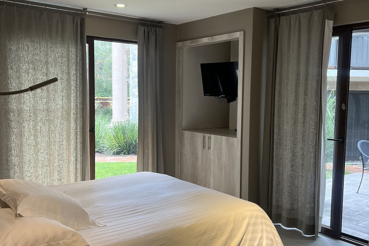 Un dormitorio moderno con una cama grande, un televisor de pantalla plana en la pared y una puerta corrediza de vidrio que da a un espacio al aire libre.