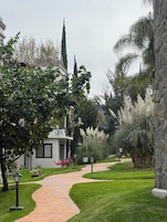 Un sendero que conduce a un edificio de fachada blanca y pared de piedra.