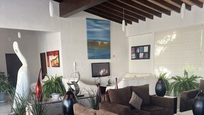 Una sala de estar moderna con un sofá modular grande, un televisor de pantalla plana y varios objetos decorativos como jarrones y plantas.