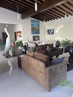Una sala de estar moderna con un sofá modular grande, un televisor de pantalla plana y varios objetos decorativos como jarrones y plantas.