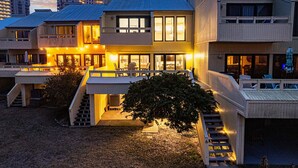 Un edifici modern d'àmbit elevat amb entrada ben il·luminada, zona d'seients exteriors i una escala que condueix als nivells superiors.