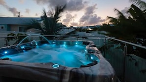 Een bubbelbad met uitzicht op de ondergaande zon en palmbomen.