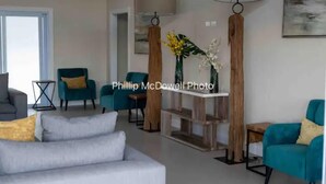 Een moderne woonkamer met een grijze bank, blauwgroene fauteuils en een houten salontafel.