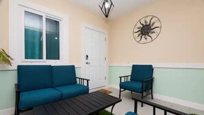 Un balcon avec un canapé bleu, un fauteuil assorti et une petite table.