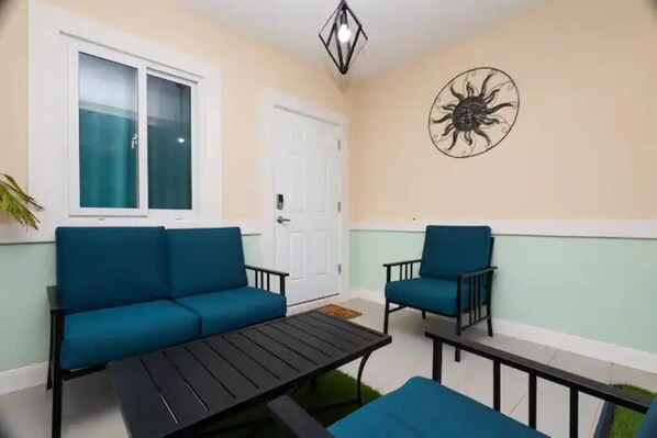 A balcony with a blue sofa, a matching armchair, and a small table.
