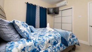Une chambre à coucher avec un lit, des rideaux, une télévision et une armoire.