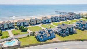 A residential area with houses, a swimming pool, and a pier in the background.