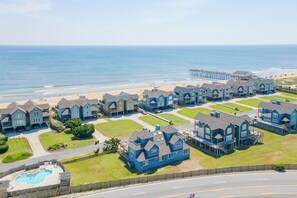 A residential area with houses, a swimming pool, and a pier in the background. - Beautiful semi-oceanfront townhouse near Kitty Hawk Pier! (Kitty Hawk)