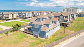 A coastal residential area with houses featuring gabled roofs and a prominent building with a green roof in the background. - Beautiful semi-oceanfront townhouse near Kitty Hawk Pier! (Kitty Hawk)