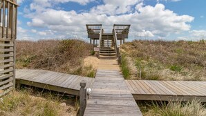 A wooden boardwalk leading to two wooden observation towers, surrounded by sand dunes and sparse vegetation. - Beautiful semi-oceanfront townhouse near Kitty Hawk Pier! (Kitty Hawk)