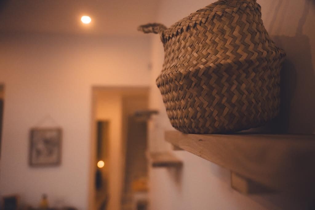 Een gevlochten mand op een houten plank in een kamer met een warme sfeer.