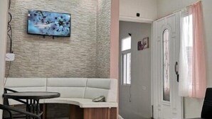 Un salon moderne avec un canapé blanc, une table ronde et un téléviseur fixé à un mur à texture.